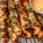 Bang Bang Chicken Skewers grilled to perfection with creamy spicy sauce, fresh herbs, and lime wedges served on a platter