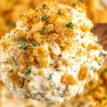 Million Dollar Chicken Casserole on a spoon with creamy chicken filling, buttery Ritz cracker topping, and a sprinkle of parsley.