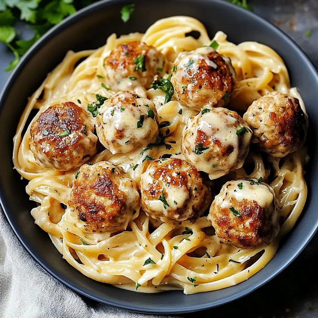 Garlic butter chicken meatballs on creamy parmesan pasta with parsley garnish