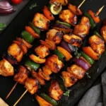 Grilled Chicken Skewers with colorful vegetables and chicken kabob marinade on a black serving platter.