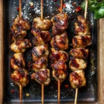 Grilled Thai Coconut Chicken Skewers sizzling with a sticky coconut glaze on a wooden tray