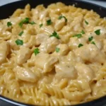 Creamy Smoky White Cheddar Honey Butter Chicken Pasta Skillet in a black pan, topped with chopped parsley for garnish.