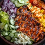 Grilled Buffalo Chicken Salad with feta, corn, cucumbers, red onions, and hot sauce in a wooden bowl.