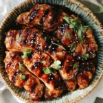 Grilled Teriyaki Chicken glazed with sauce, garnished with sesame seeds and cilantro in a rustic ceramic bowl.