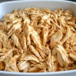 Tender Slow Cooker Mexican Shredded Chicken in a white serving dish, ready for tacos or bowls.