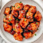 Bowl of Sweet and Spicy Sticky Chicken topped with sesame seeds and green onions