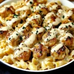 Creamy Garlic Butter Chicken Bites with Creamy Pasta topped with fresh herbs in a white bowl.