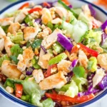 Colorful bowl of Crunchy Thai Chicken Salad with shredded vegetables, grilled chicken, peanuts, and fresh herbs.