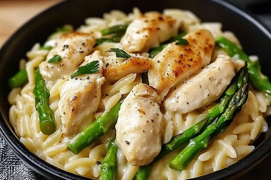 Creamy Parmesan Orzo with Chicken and Asparagus served in a black bowl