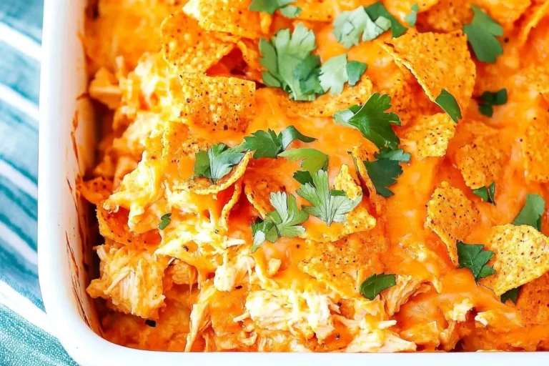 Close-up of cheesy Doritos Chicken Casserole topped with fresh parsley in a white baking dish.