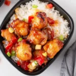 Bowl of Copycat Sweet Fire Chicken with rice, bell peppers, and pineapple chunks.