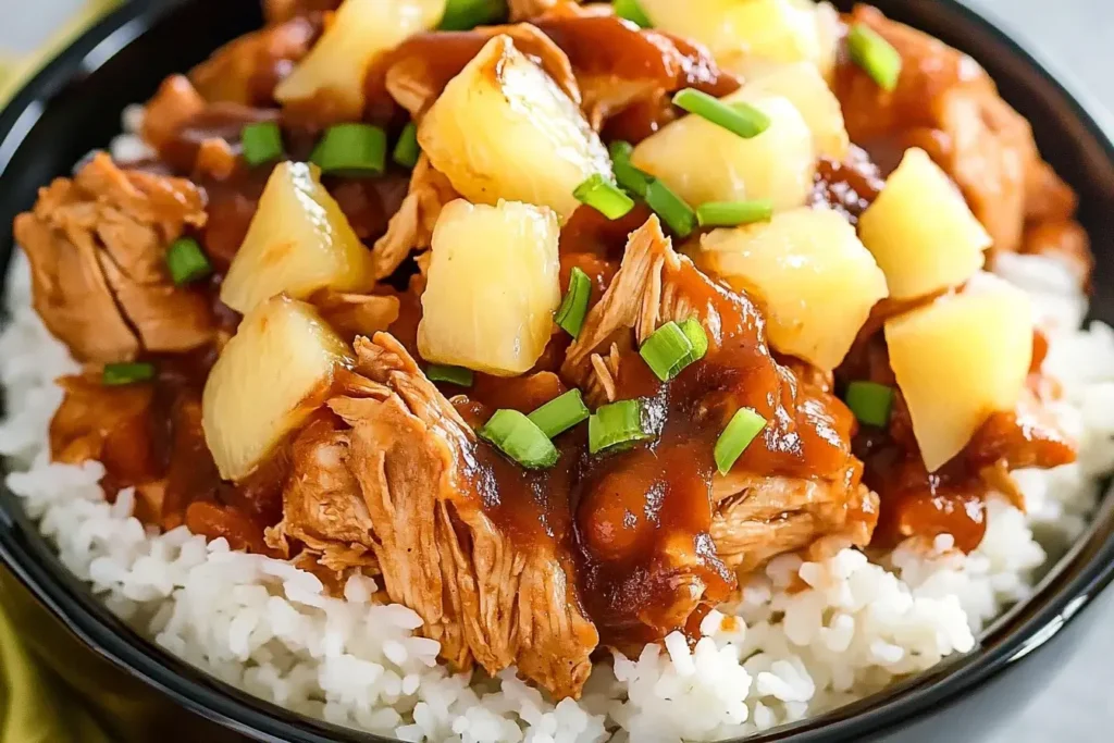 Close-up of Crockpot Pineapple BBQ Chicken served over white rice with pineapple chunks and chopped green onions.