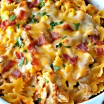 Close-up of cheesy BBQ Ranch Chicken Casserole topped with crispy bacon and parsley in a white baking dish.