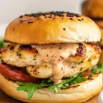 Grilled Chicken Burgers with Bang-Bang Sauce served on a toasted bun with fresh greens and tomato.