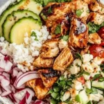 Cava Honey Harissa Chicken Bowls with grilled chicken, rice, cucumbers, and fresh toppings in a white ceramic bowl.