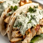 Close-up of Shredded Chicken Tacos with Creamy Chimichurri Sauce topped with herbs on warm tortillas