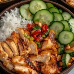 Sweet Chili Rotisserie Chicken Bowls with sliced cucumbers, jasmine rice, and chili-topped chicken in a dark ceramic bowl.