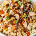 BBQ Chicken Pasta Salad in a white bowl with colorful veggies, drizzled with BBQ sauce