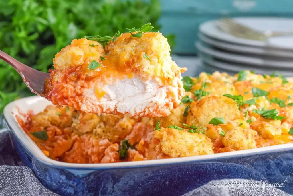 A close-up of Cheddar Bay Chicken Bake showing a juicy piece of chicken topped with cheesy biscuit crust and marinara sauce.