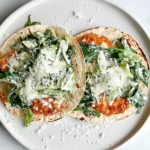 Smash Chicken Caesar Tacos topped with romaine, Caesar dressing, and shaved parmesan on a white plate