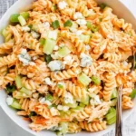 A bowl of Buffalo Chicken Pasta Salad with rotini pasta, shredded chicken, celery, carrots, and crumbled blue cheese.