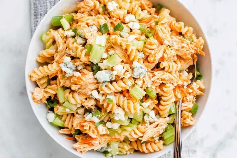 A bowl of Buffalo Chicken Pasta Salad with rotini pasta, shredded chicken, celery, carrots, and crumbled blue cheese.