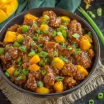 Mango Chicken Stir Fry featuring crispy chicken, sweet mango chunks, and green onions in a glossy sauce served in a dark bowl.