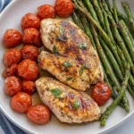 Oven Baked Balsamic Chicken served with roasted cherry tomatoes and asparagus on a white plate.