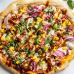 Grilled Summer BBQ Chicken Pizza topped with corn, red onions, cilantro, and drizzled with BBQ sauce on a golden crust.