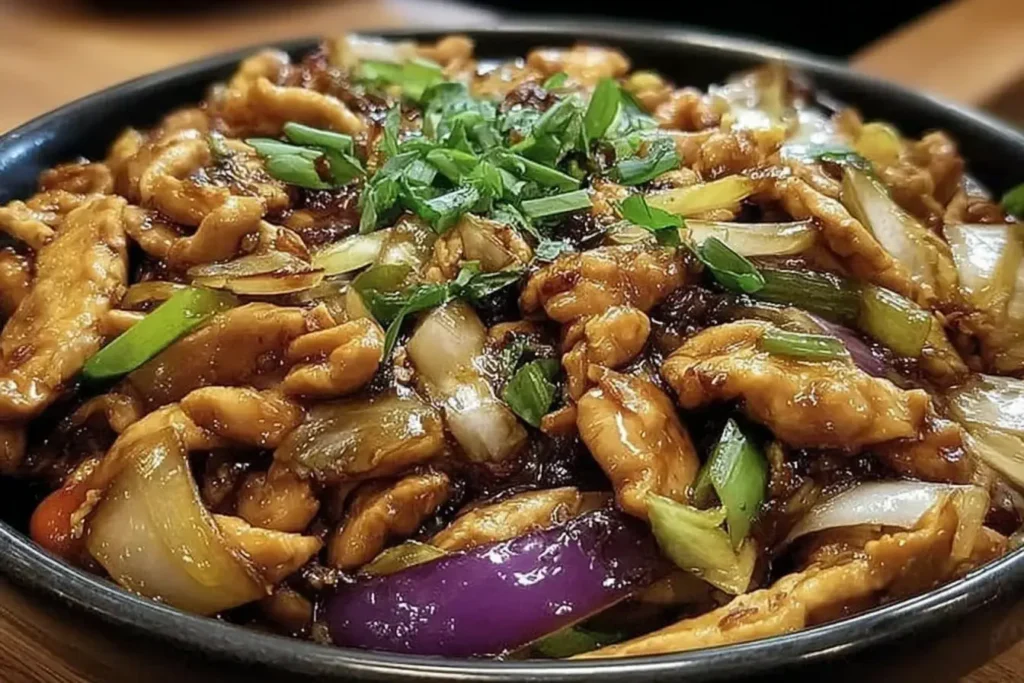 Moo Shu Chicken Recipe featuring tender chicken strips stir-fried with vibrant vegetables and savory sauce, served in a black bowl.
