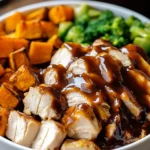 Close-up of BBQ Chicken and Roasted Sweet Potato Bowls topped with rich BBQ sauce and served with steamed broccoli.