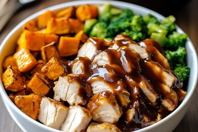 Close-up of BBQ Chicken and Roasted Sweet Potato Bowls topped with rich BBQ sauce and served with steamed broccoli.