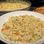 Close-up of Creamy Chicken Pot Pie Orzo served in a white bowl with crusty bread