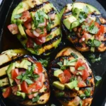 Grilled California Avocado Chicken topped with fresh avocado, tomatoes, and basil in a cast iron skillet