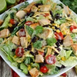 Tex-Mex Chopped Chicken Salad with grilled chicken, black beans, corn, cherry tomatoes, and creamy dressing on a white plate
