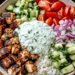 Healthy and Delicious Chicken Gyro Bowls with grilled chicken, rice, tzatziki sauce, fresh cucumber, cherry tomatoes, and red onion.