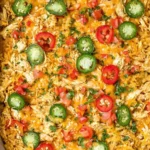 Baked Jalapeño Buffalo Chicken Casserole topped with melted cheese, sliced jalapeños, and fresh diced tomatoes in a white baking dish.