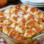 Freshly baked Apple Bubble Up Casserole in a glass dish, featuring golden biscuit pieces and gooey caramelized apple filling.