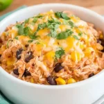 Slow Cooker Chicken Burrito Bowls topped with melted cheese, black beans, corn, and fresh cilantro in a white bowl