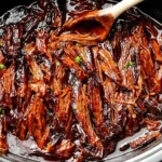 Slow Cooker BBQ Beef Brisket shredded and coated in rich barbecue sauce inside a slow cooker.