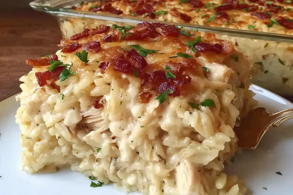 Slice of Dump-and-Bake Chicken Alfredo Rice Casserole with melted cheese, bacon, and parsley on a white plate.