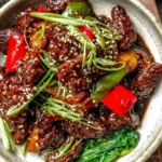 Mongolian Beef topped with sesame seeds, green onions, and bell peppers served in a ceramic bowl.