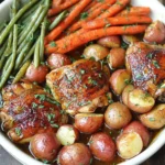 Slow Cooker Honey Garlic Chicken and Veggies served in a white dish with glazed chicken thighs, baby red potatoes, carrots, and green beans.
