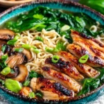 A close-up bowl of Ginger Glazed Chicken Ramen with sliced chicken, noodles, mushrooms, and fresh greens in savory broth.