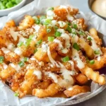 Crispy Louisiana Voodoo Fries topped with melted cheese, bacon, and green onions, drizzled with spicy ranch sauce.