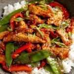 Firecracker Chicken Stir Fry with bell peppers, snap peas, and savory sauce served over white rice in a bowl