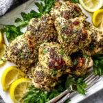 Plate of Oven Baked Greek Chicken Thighs garnished with lemon slices and fresh parsley