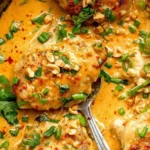 Creamy One Pan Coconut Lime Chicken garnished with peanuts, cilantro, and spring onions in a skillet