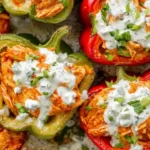 Buffalo Chicken Stuffed Peppers topped with dairy-free ranch and fresh herbs in a baking dish.
