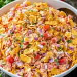 Colorful bowl of Fritos Chili Cheese Salad with corn, red bell peppers, purple onion, cheddar cheese, and chili Fritos mixed in creamy dressing